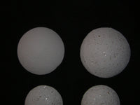 Image of four white spherical objects resembling Crystal Pearls on a black background.
