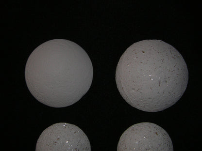 Image of four white spherical objects resembling Crystal Pearls on a black background.