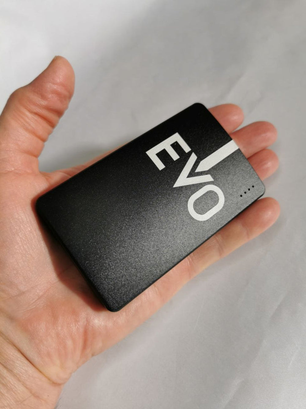 Hand holding a black Portable Device 'EVO' branding on a light gray background