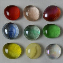 Nine colorful marbles slightly flattened (Energy Cells) on a textured surface