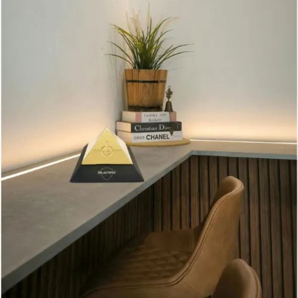 Evo Pyramid on a modern desk surrounded by books and a decorative plant, showcasing EMF protection design.