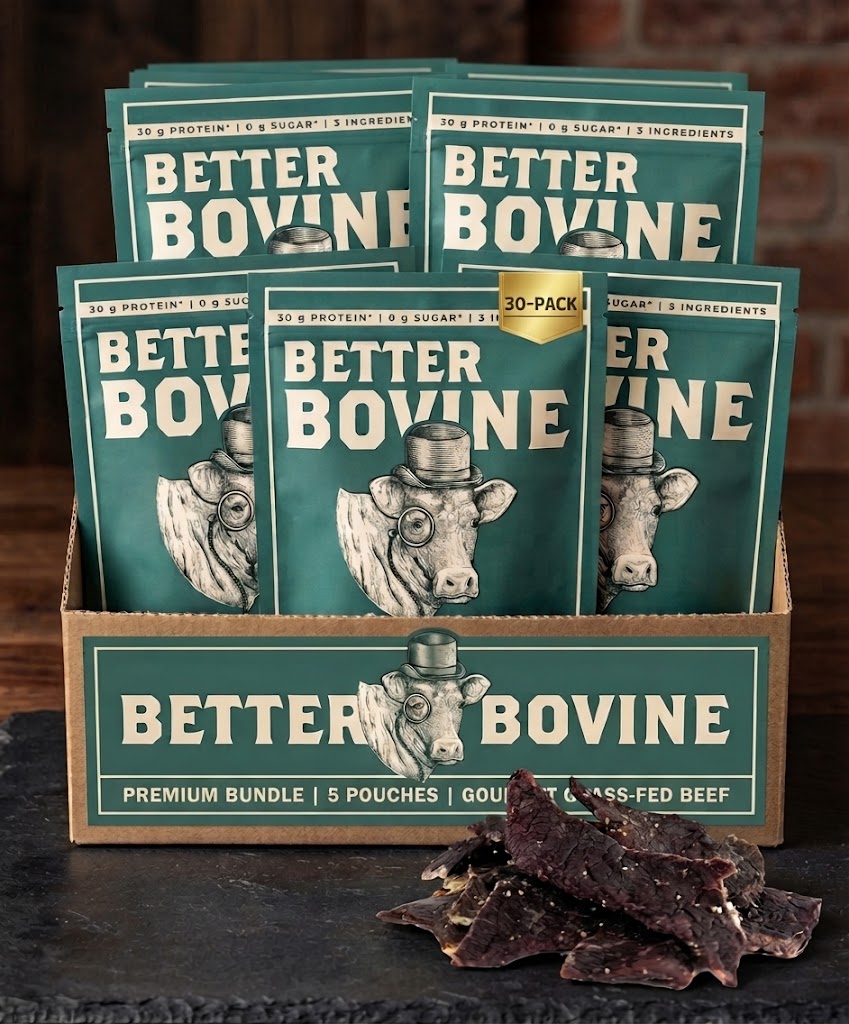 A display box filled with multiple Better Bovine beef pouches, with a few dried beef jerky slices placed in front, set on a dark tabletop against a rustic brick background.