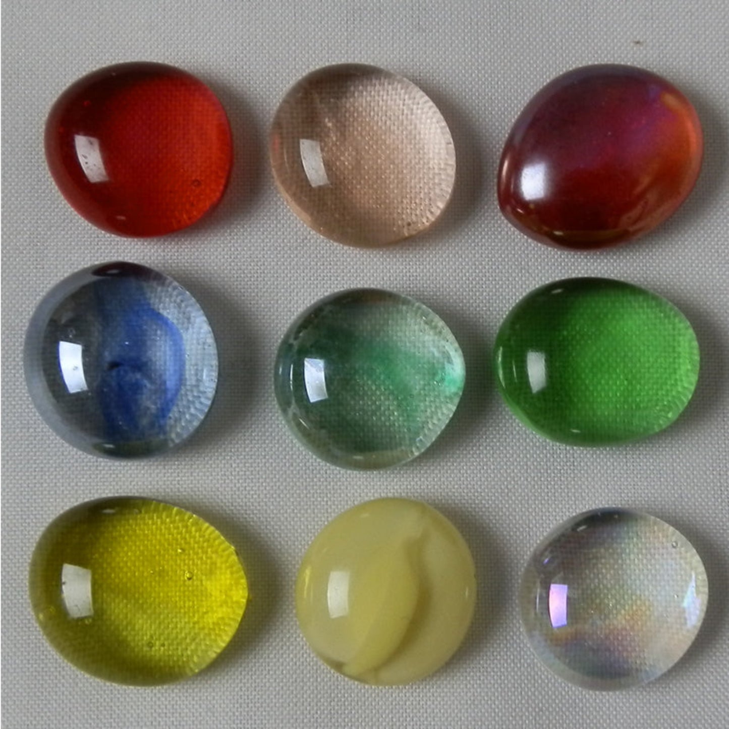 Nine colorful glass balls on a textured surface
