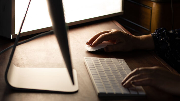 Person using a laptop with a warm glow on a wooden desk