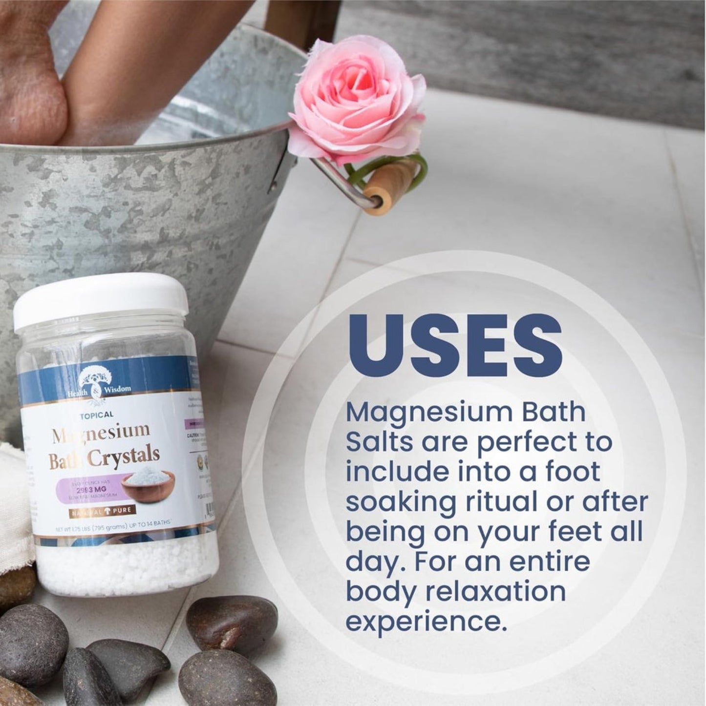 Bottle of magnesium bath crystals with Uses and a bucket of water, rose, and stones on a light background.