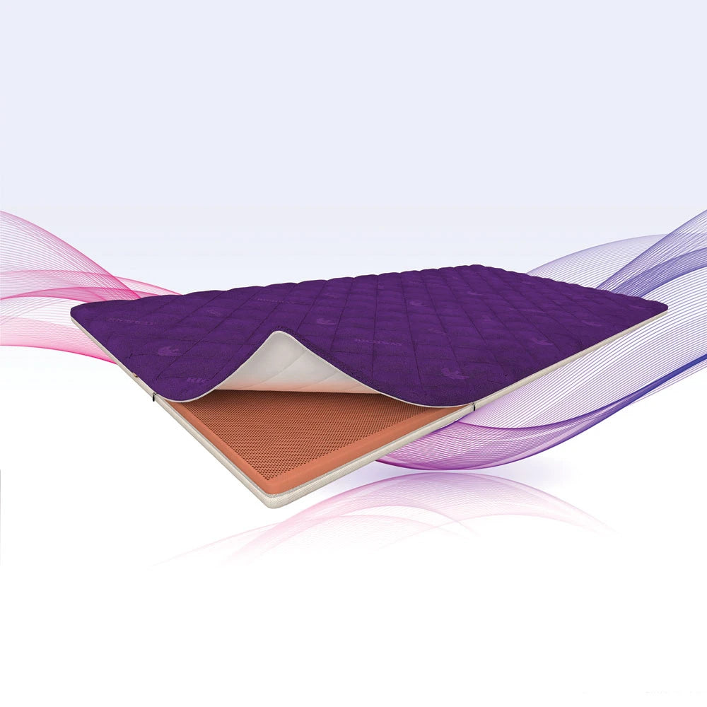 A floating mattress topper or mattress slice shown at an angle, with a purple quilted top layer and a peach-colored underside, set against a white background with pink and purple abstract wave graphics.