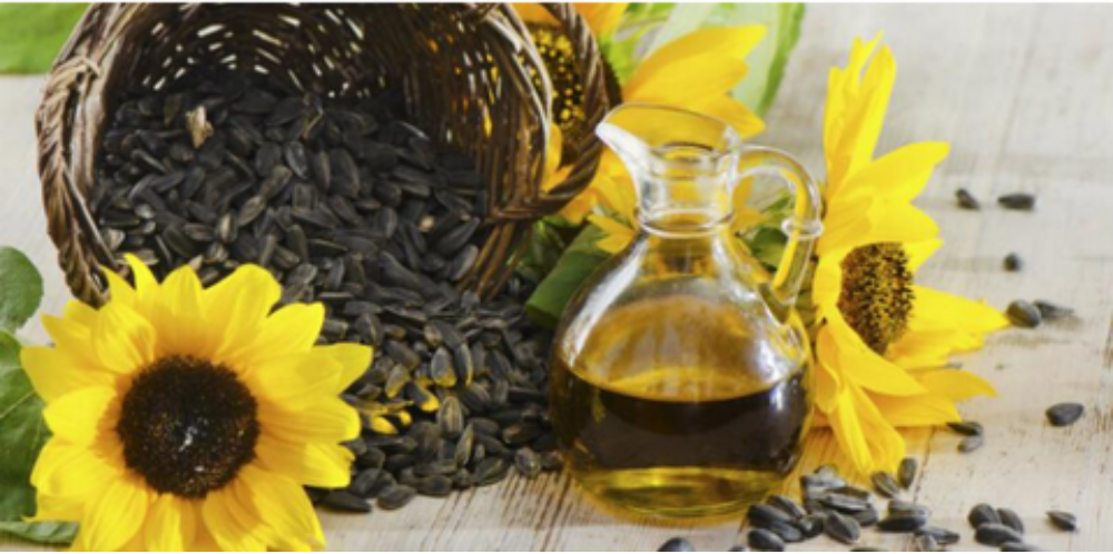 sunflower seeds, oil, and flowers on a wooden surface.