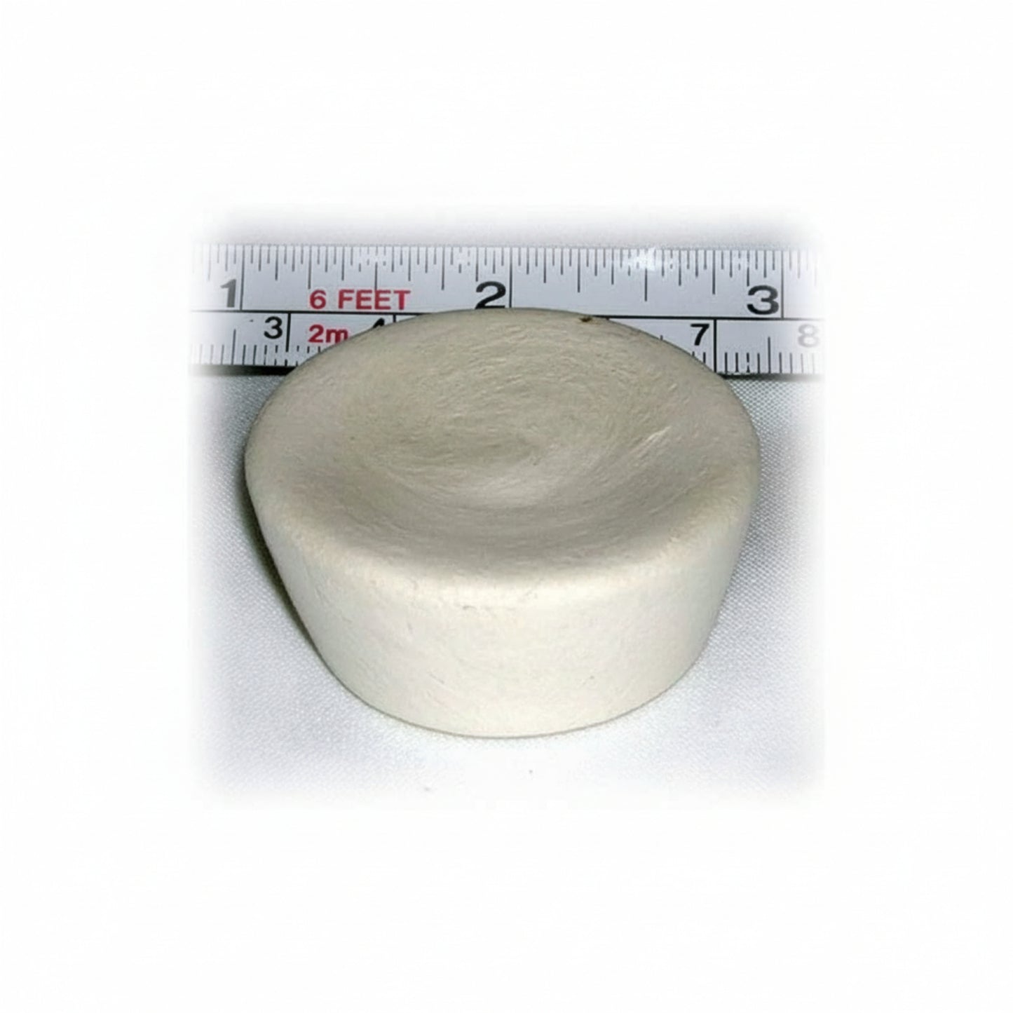 Round ivory cupcake-shaped device with a ruler showing its size on a white background