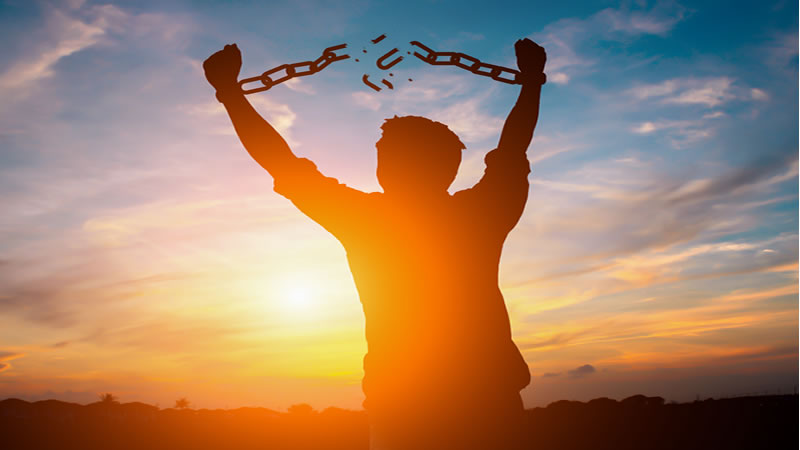 man with arms up breaking free from thick chain